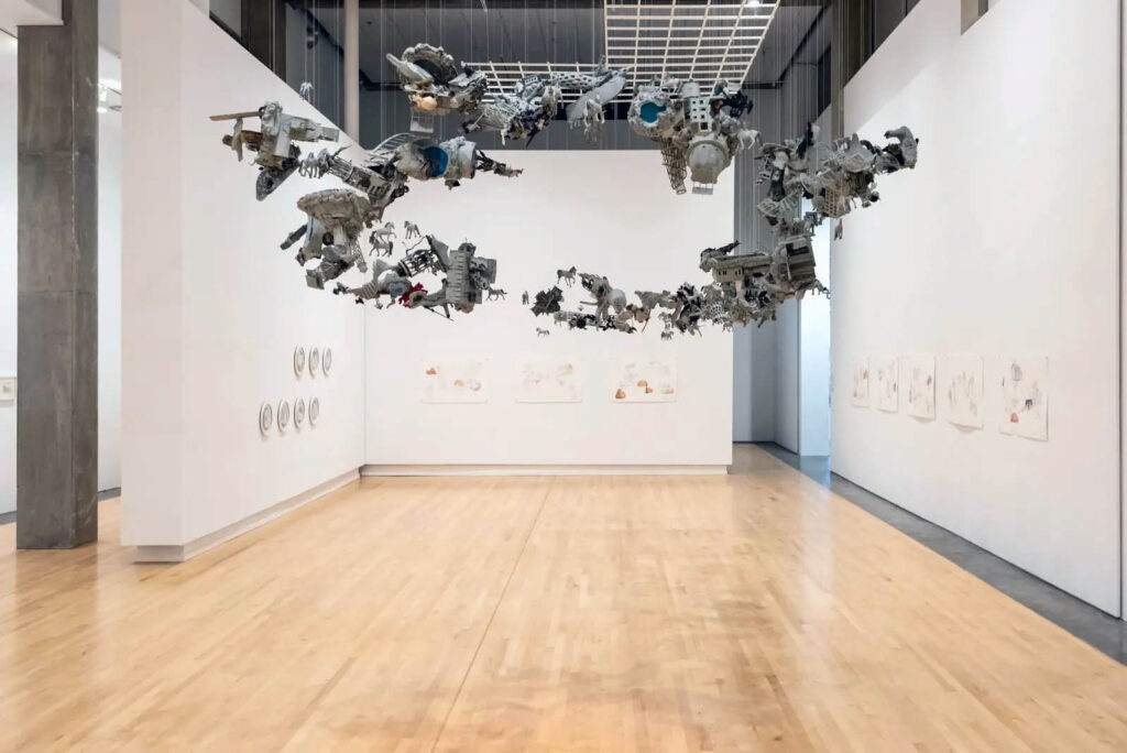 The Herd - a hanging sculpture of kit bashed models with drawings hanging on the walls in the background.